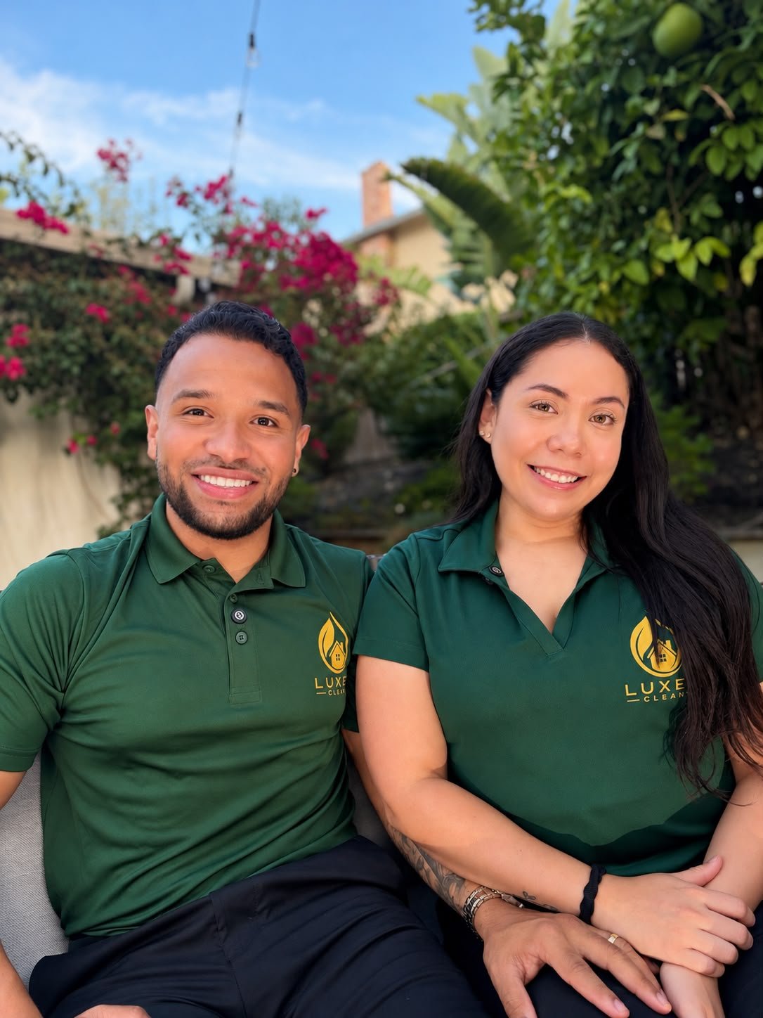 Alex and Daniela, the partners behind Luxen Clean, smiling together in their green uniforms