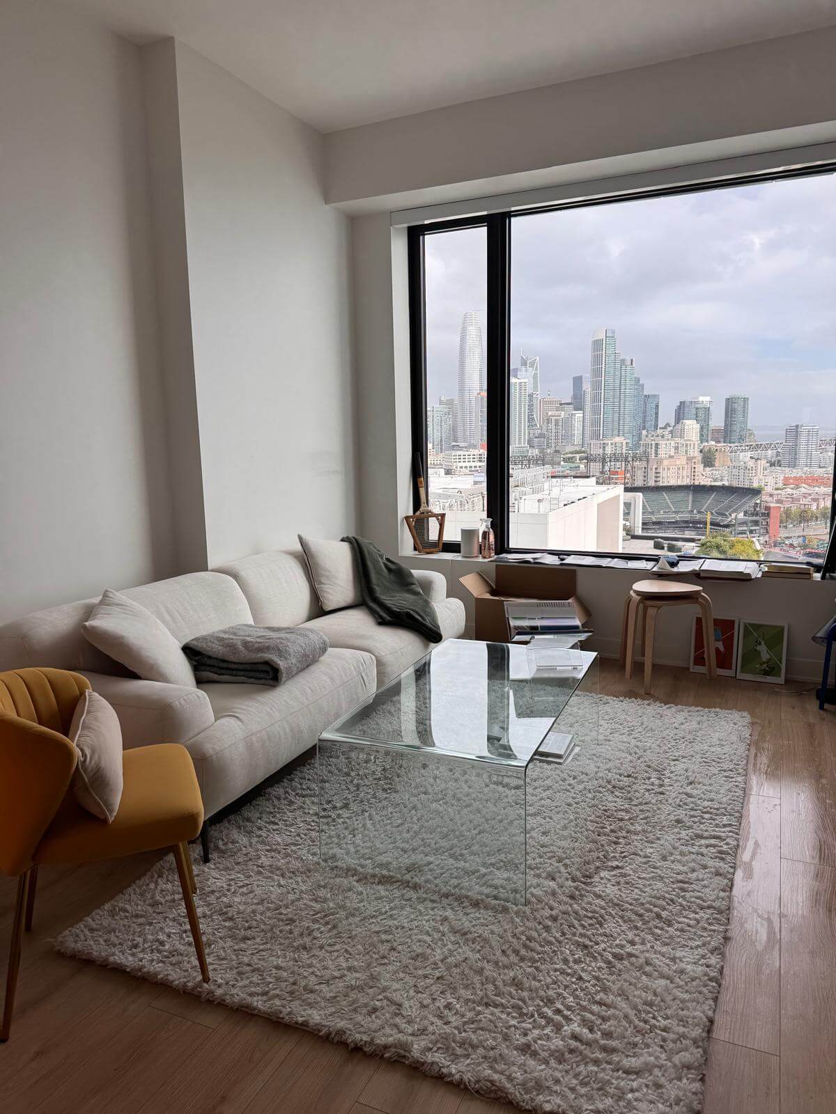Living room with a cream sofa, glass coffee table and a city view